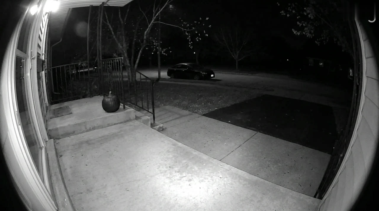 An empty porch at night as seen through a video doorbell camera.